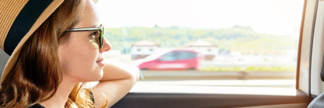 Woman with sunglasses and straw hat riding a taxi