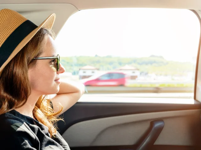 Woman with sunglasses and straw hat riding a taxi