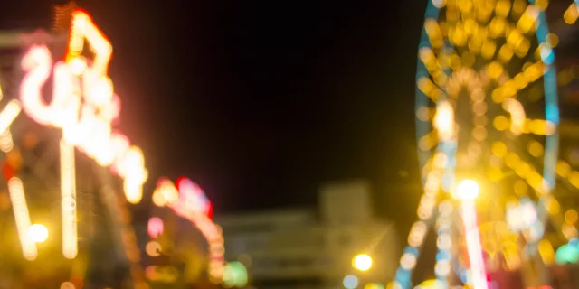 Defocused and blur image of Amusement park at night - ferris wheel and rollercoaster in bokeh