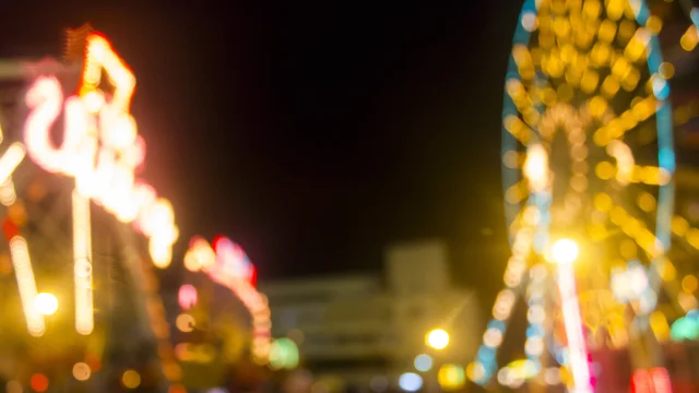 Defocused and blur image of Amusement park at night - ferris wheel and rollercoaster in bokeh