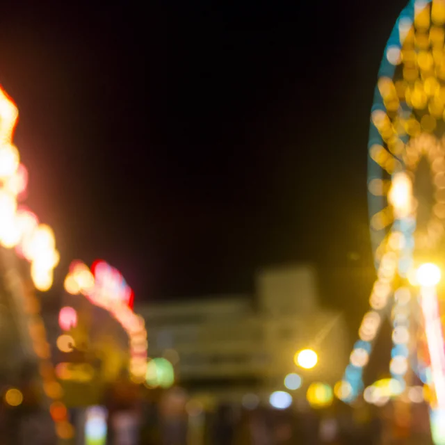 Defocused and blur image of Amusement park at night - ferris wheel and rollercoaster in bokeh